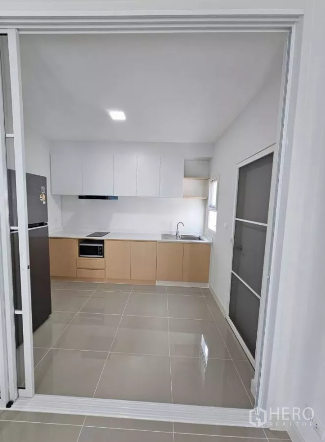 Detached House for rent in Bang Phli, Samut Prakan - Minimal kitchen with built-in cabinets, sink, induction cooktop and microwave.