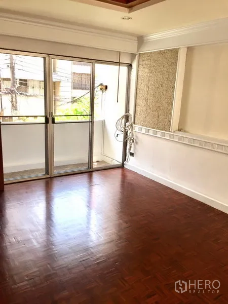 Townhouse for rent in Watthana, Bangkok - Sunlit room featuring wood flooring and sliding doors opening to a small balcony.