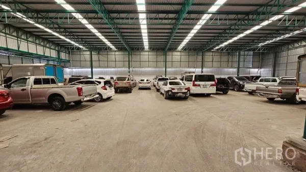 Warehouse for rent in Bang Bon, Bangkok - Large warehouse floor with parked vehicles, steel trusses, and bright LED lighting.