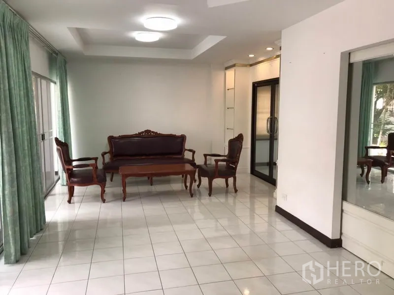 独立式住宅 出租在Phra Khanong, Bangkok - 明亮客厅，古典木质沙发组，地砖与大幅推拉门。