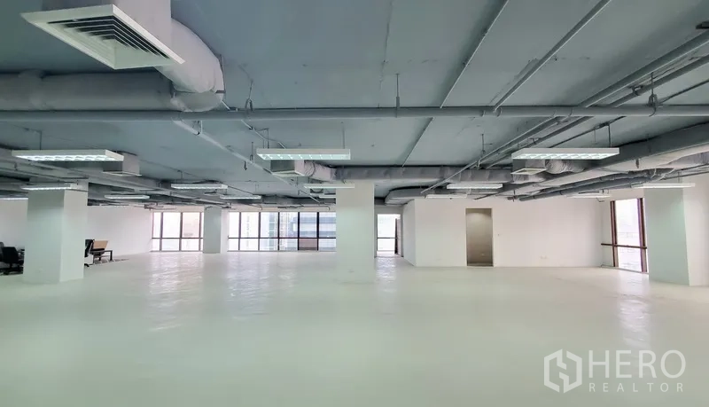 Office Space for rent in Watthana, Bangkok - Spacious white‑floor workspace with columns, ceiling air‑conditioning, and bright window frontage.