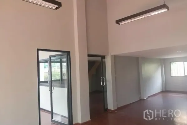Retail Space for rent - High-ceiling hall with suspended linear lights and multiple glass doors for customer access.