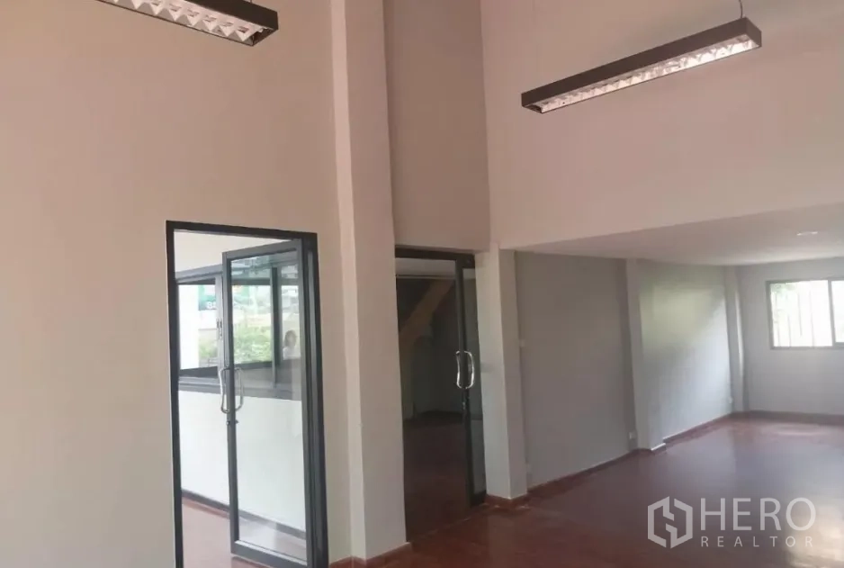 Retail Space for rent - High-ceiling hall with suspended linear lights and multiple glass doors for customer access.