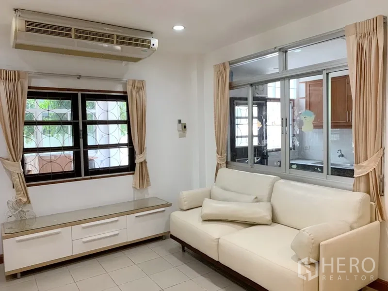 Detached House for rent in Khlong Toei, Bangkok - Cozy sitting area with white sofa, built-in console, air-conditioning and window to the kitchen.
