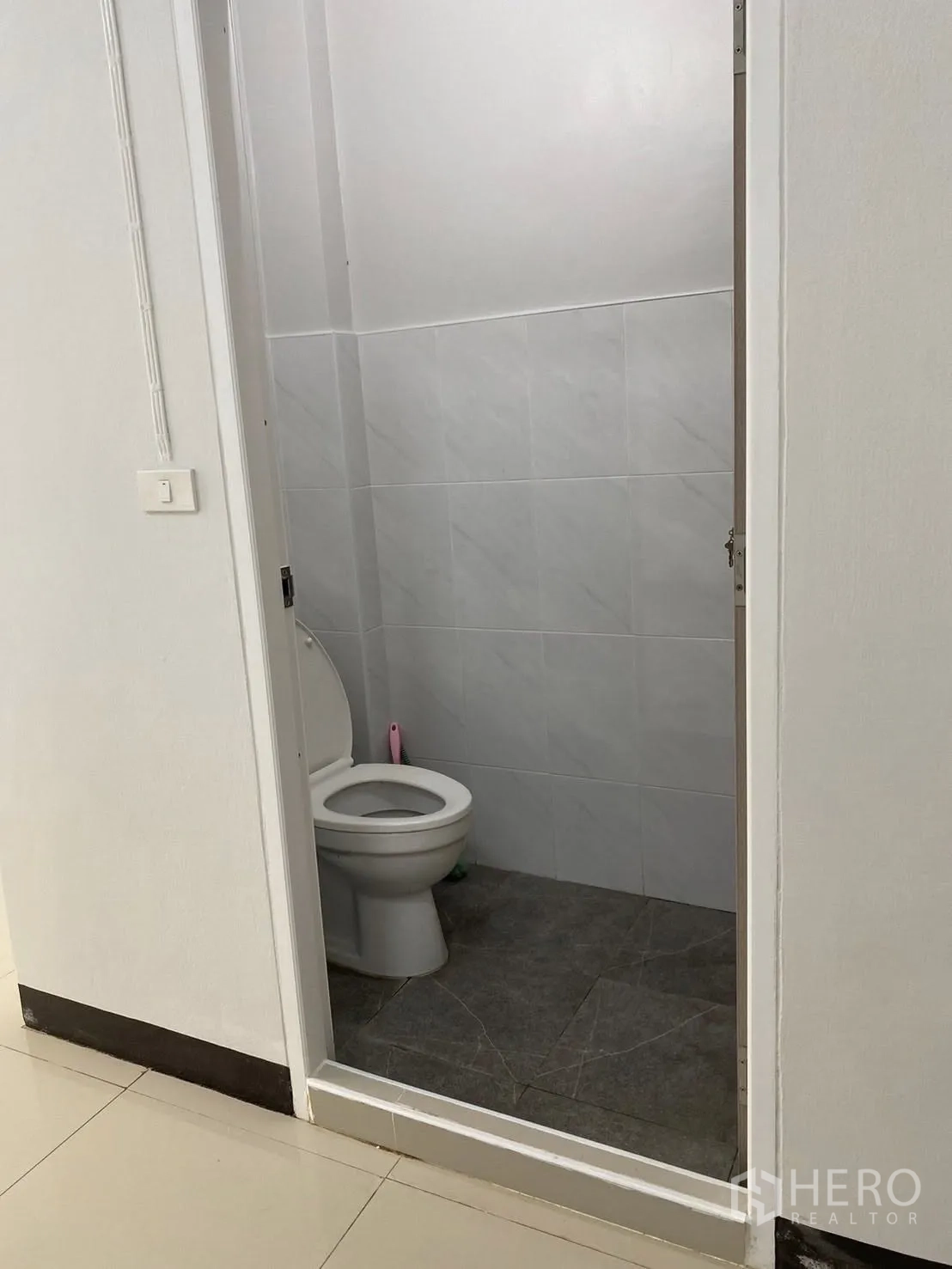 Townhouse for rent in Huai Khwang, Bangkok - Clean ground-floor guest bathroom with new grey-and-white wall and floor tiles.
