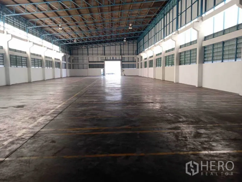 Factory for rent in Samut Prakan - Central view across the 1,200 sqm factory hall toward a large entry door for trucks.