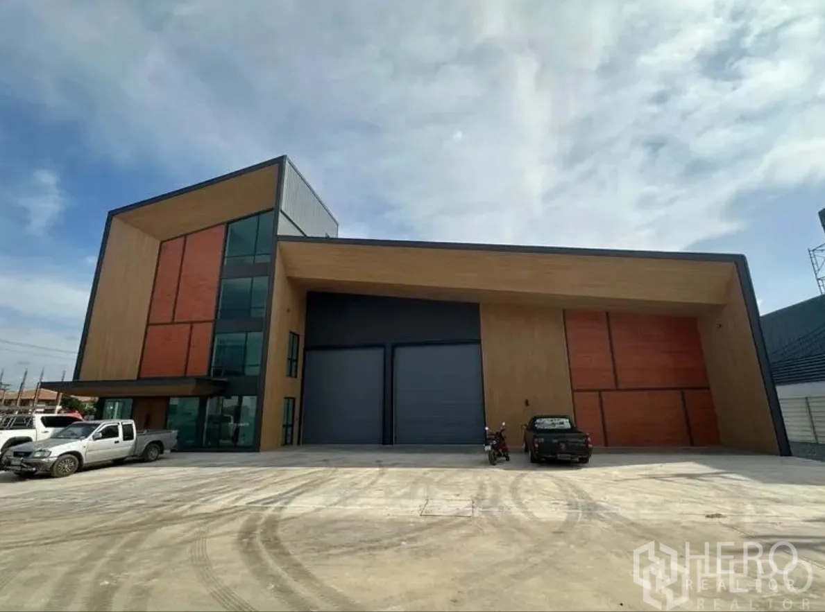 Warehouse for sale in Lam Luk Ka, Pathum Thani - Front elevation of contemporary warehouse with twin grey shutters and spacious concrete forecourt.