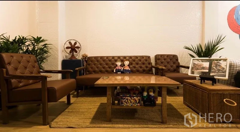 Townhouse for rent in Khlong Toei, Bangkok - Cozy sitting area with vintage leather sofas, coffee table and indoor plants.