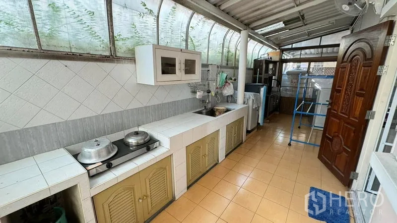 Detached House for sale in Mueang Pathum Thani, Pathum Thani - Outdoor Thai kitchen under a roof with long countertops, sink and storage cabinets.