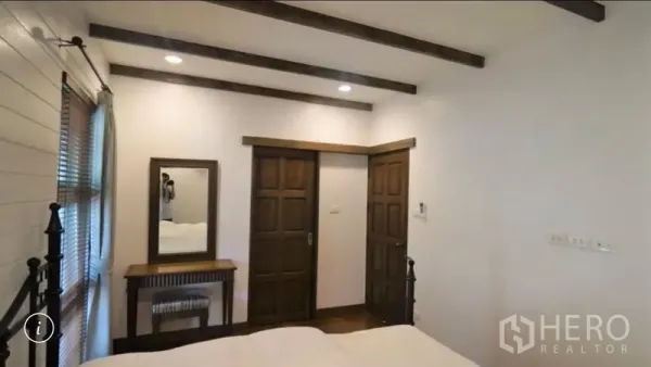 Detached House for rent or sale in Bang Phli, Samut Prakan - Cozy bedroom with wooden double doors, dressing table and ceiling beams.