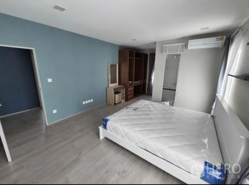Detached House for rent in Prawet, Bangkok - Spacious second bedroom with blue accent wall, built-in wardrobe, air conditioning, and en-suite access.