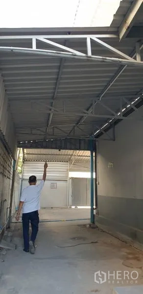 Warehouse for rent in Lam Luk Ka, Pathum Thani - Covered passageway with beam structure and sliding gate entry beside the warehouse.