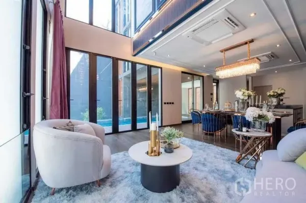 Detached House for sale in Prawet, Bangkok - Double‑height living and dining area with floor‑to‑ceiling glass doors opening to a private pool.