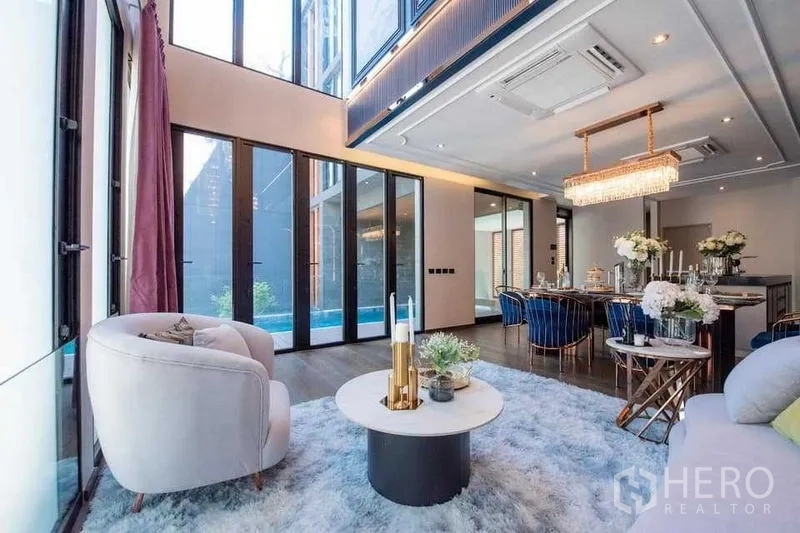 Detached House for sale in Prawet, Bangkok - Double‑height living and dining area with floor‑to‑ceiling glass doors opening to a private pool.
