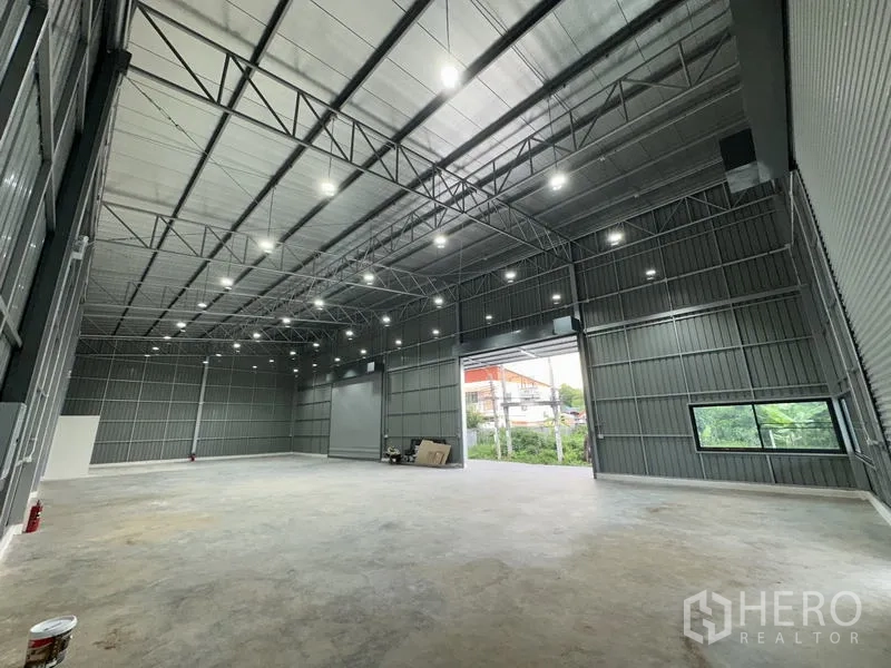 Warehouse for rent in Bang Kapi, Bangkok - Bright warehouse hall with steel trusses, LED lights and a side window by the entrance.