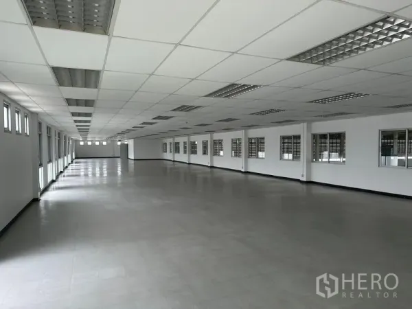 Factory for rent in Pathum Thani - Large office workspace with drop ceiling, fluorescent lights, and rows of windows.