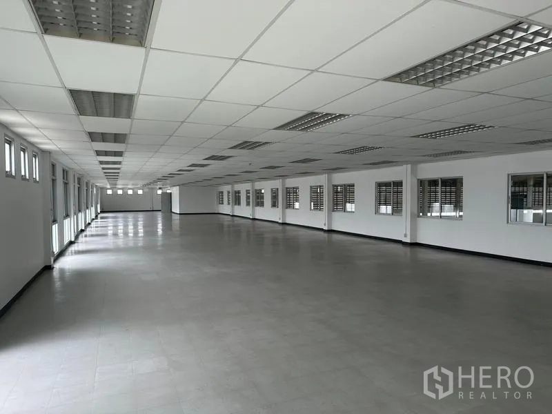 Factory for rent in Pathum Thani - Large office workspace with drop ceiling, fluorescent lights, and rows of windows.