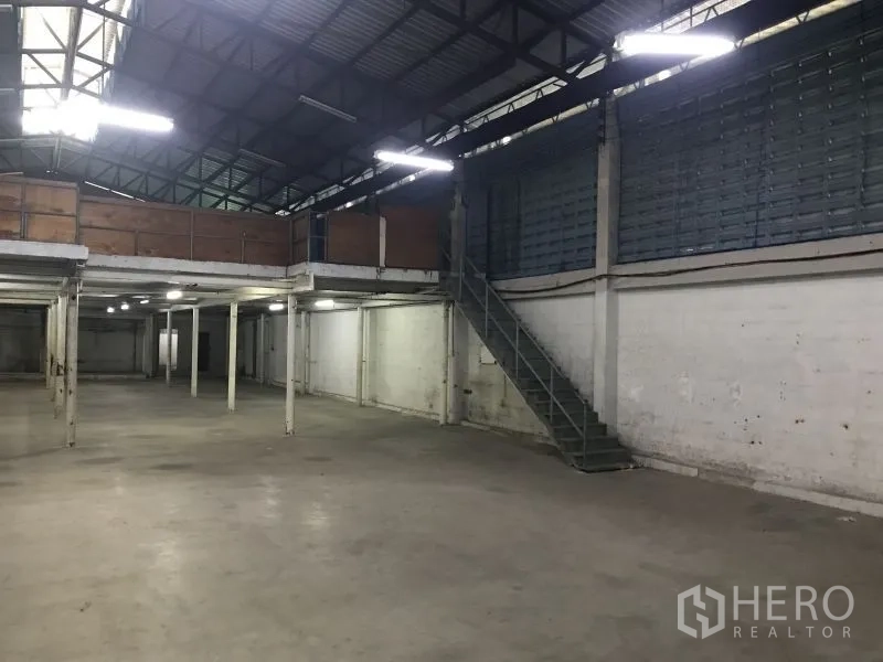 Factory for rent or sale in Krathum Baen, Samut Sakhon - Warehouse hall with metal staircase to mezzanine and ample floor space for racking or lines.