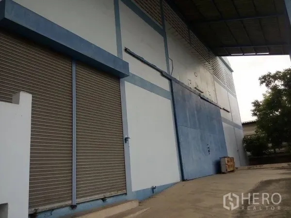 货栈 出租在Min Buri, Bangkok - 仓库外立面，卷闸门与带顶装卸区。