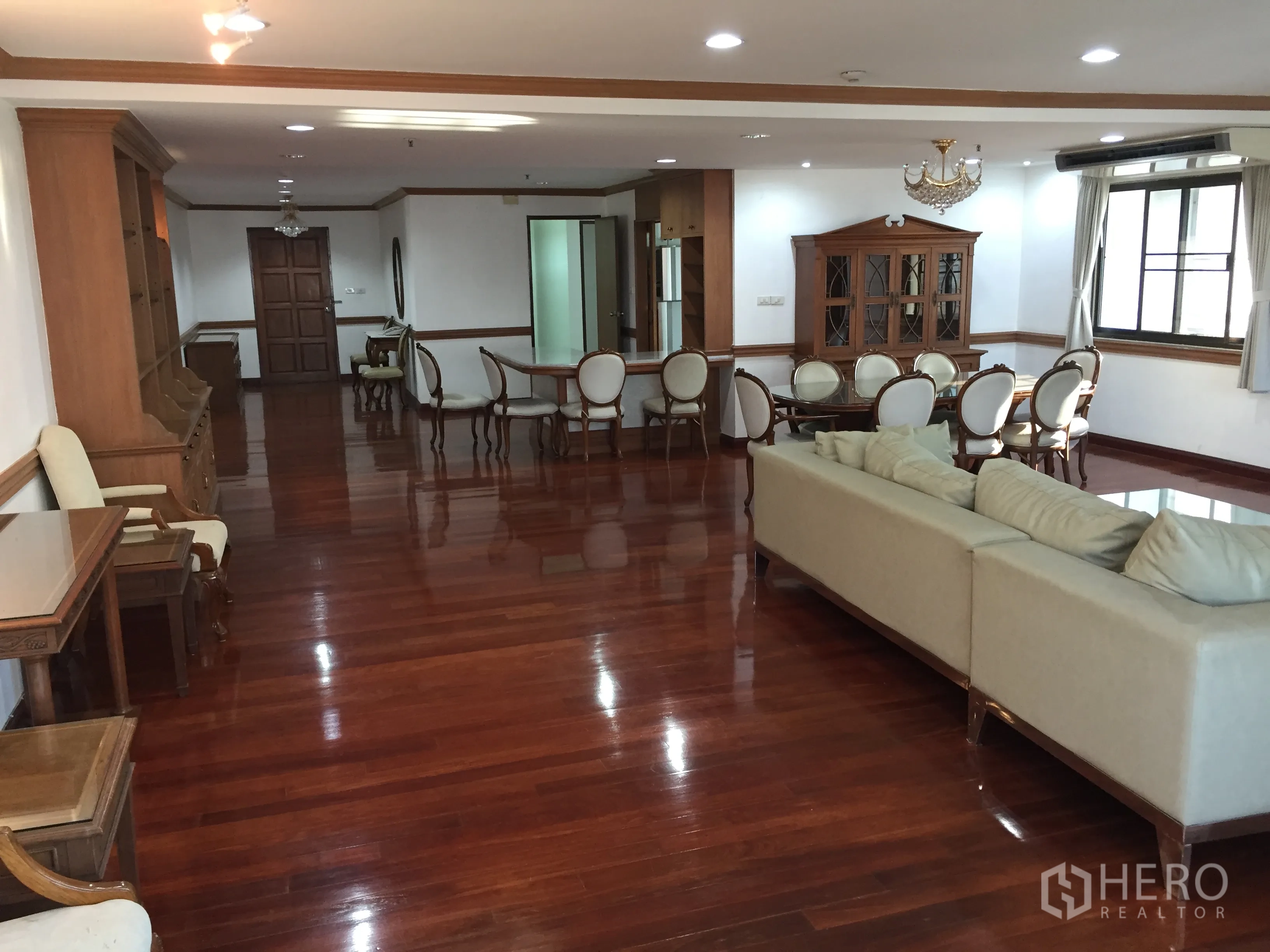 Condominium for rent in Watthana, Bangkok - Open-plan living and dining area with sofa set, chandelier and rich wooden flooring.