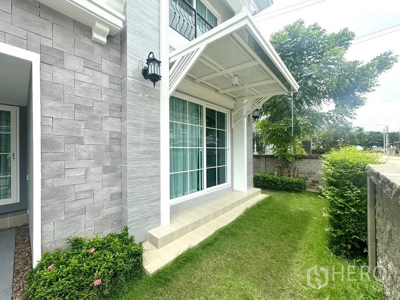 Detached House for rent - Side facade with sliding glass doors, stone cladding and small garden.