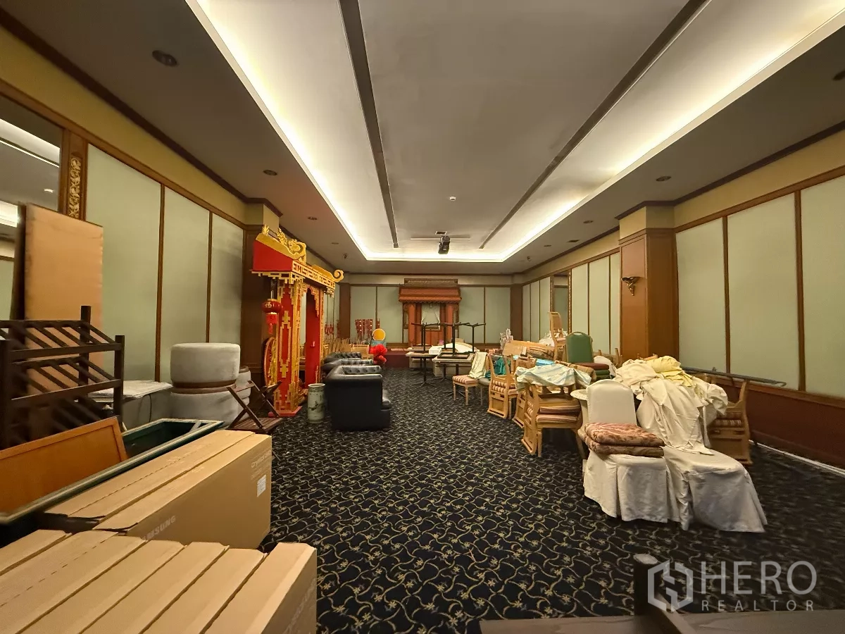 Retail Space for rent in Pathum Wan, Bangkok - Large carpeted function room with cove lighting, wood wall panels and stored furniture.