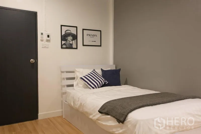 Townhouse for rent in Sathon, Bangkok - Cozy single bedroom with white bed, grey accent wall, and minimalist decor.