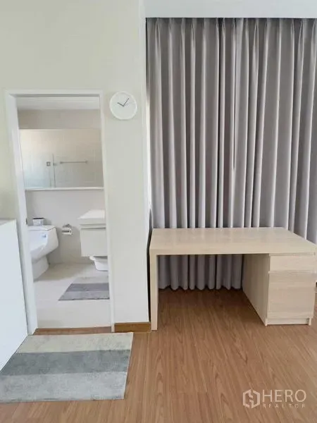 Detached House for rent or sale in Bang Khen, Bangkok - Study nook with light wood desk beside an ensuite bathroom with glass shower.