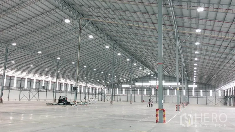 Warehouse for rent in Si Racha, Chon Buri - Spacious warehouse interior with high steel truss roof, bright lighting and polished concrete floor.