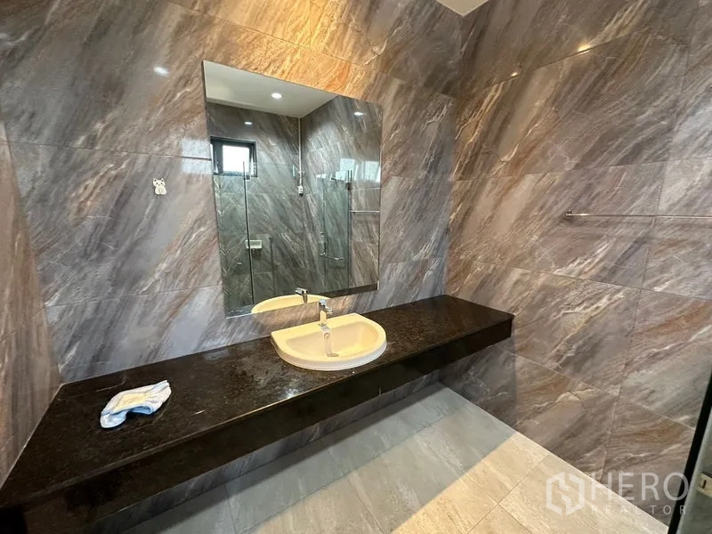 Factory for rent or sale in Lam Luk Ka, Pathum Thani - Modern bathroom with a large mirror and long granite countertop.