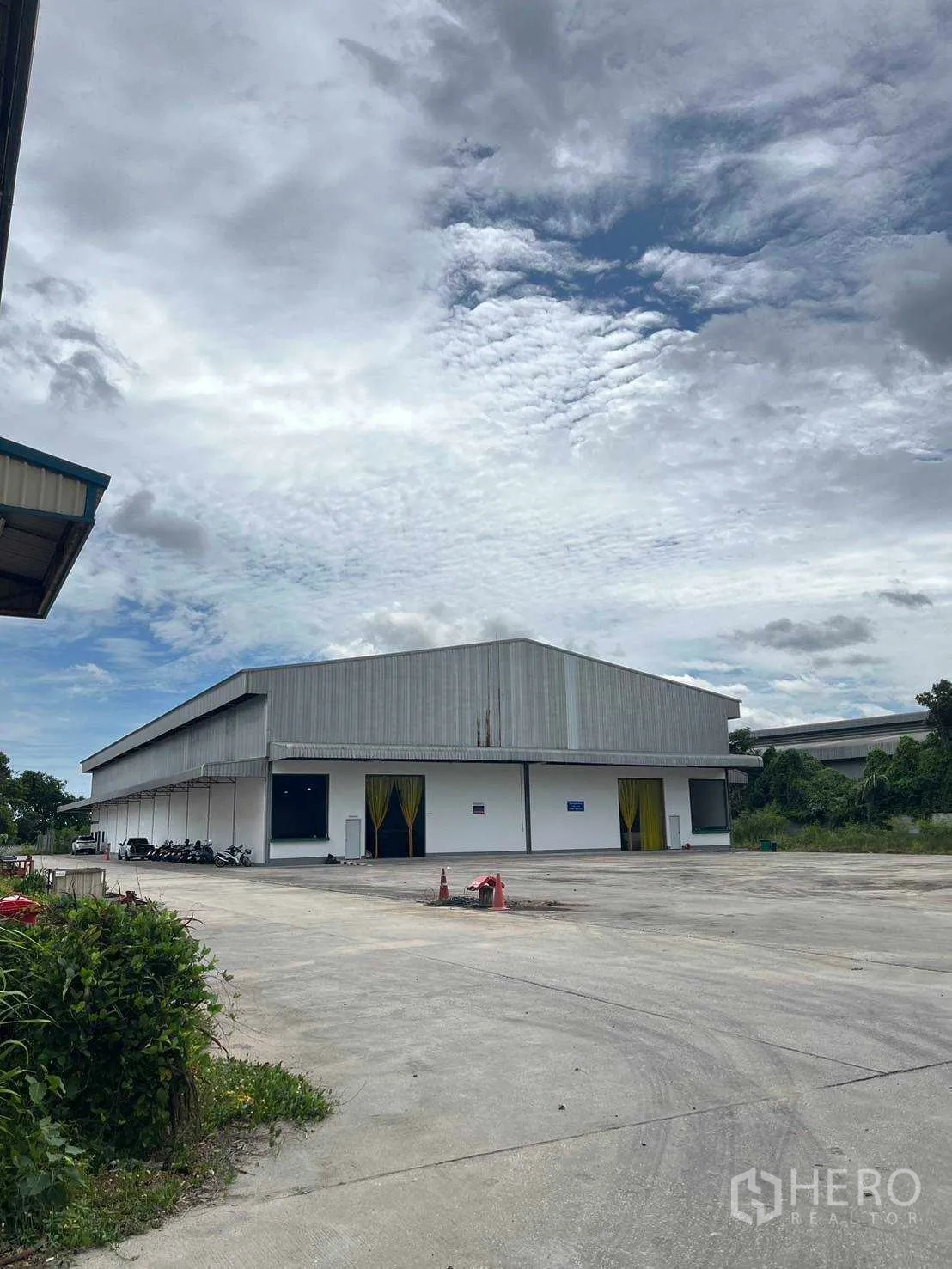Factory for sale in Nikhom Phatthana, Rayong - Front of warehouse showing loading bays and a spacious concrete parking apron.