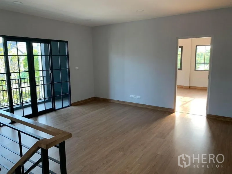Detached House for rent or sale in Bang Phli, Samut Prakan - Upstairs family area with wood floors and sliding doors opening to a balcony