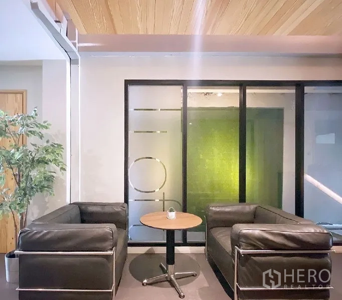 Office Space for rent in Bang Rak, Bangkok - Cozy lobby with two black leather sofas, a round coffee table, and a frosted glass partition in a Bang Rak office.