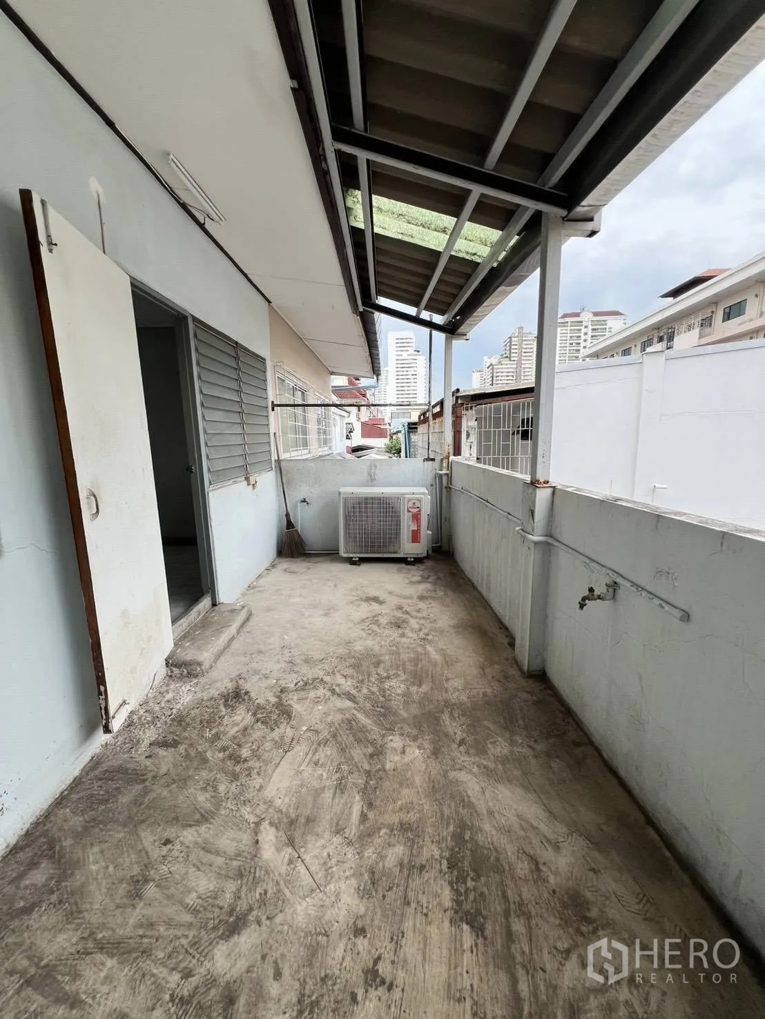 Townhouse for rent in Watthana, Bangkok - Extended covered terrace with AC unit and city views.