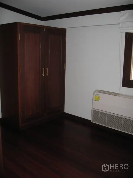 Detached House for rent in Watthana, Bangkok - Compact bedroom with freestanding wardrobe and wall AC.