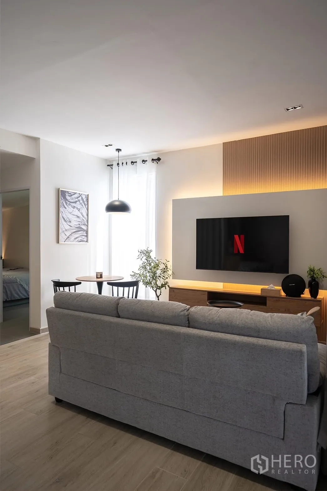 Detached House for rent in Huai Khwang, Bangkok - Sofa facing TV in a cozy lounge with wood floors and pendant light.