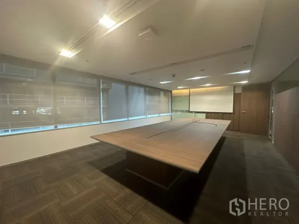 Office Space for rent in Khlong Toei, Bangkok - Modern boardroom featuring a large wooden conference table, carpet flooring, and roller blinds.