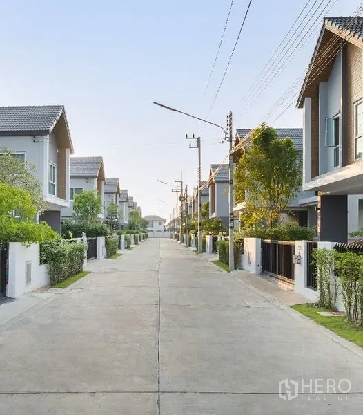 Detached House for sale in Lam Luk Ka, Pathum Thani - Quiet residential street lined with modern houses, trees and streetlights inside the estate.