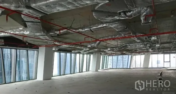 办公空间 出租 - 毛坯办公楼层，裸露风管与红色消防管线，四周落地窗俯瞰曼谷天际线