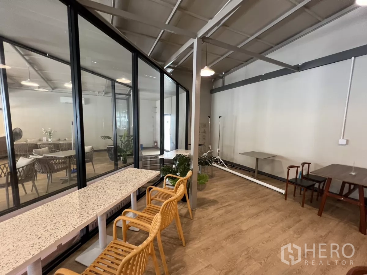 Retail Space for rent in Khlong Toei, Bangkok - Glass-walled room beside seating area with wood-look flooring and rattan chairs in a modern retail setting.