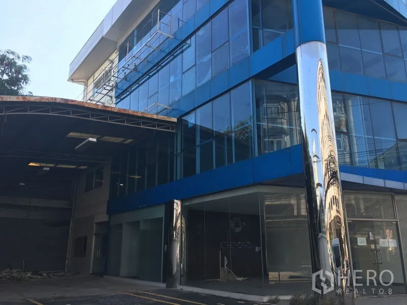 Warehouse for rent in Suan Luang, Bangkok - Modern glass-fronted warehouse-office building with reflective column and covered loading area in Suan Luang, Bangkok.