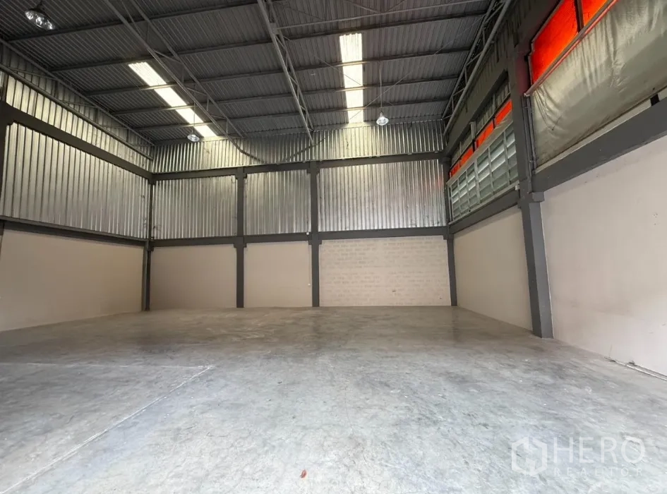 Factory for rent in Khlong Luang, Pathum Thani - Large factory hall with ventilated side panels and orange translucent sunshades.