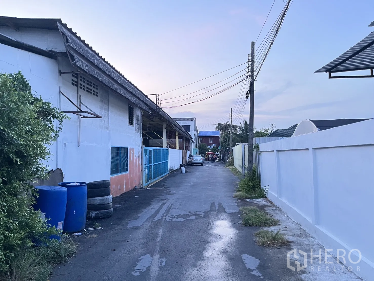 Warehouse for rent in Chatuchak, Bangkok - Quiet access lane beside the warehouse with boundary walls and utility poles.