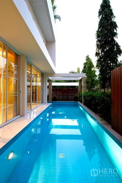 Detached House for rent in Watthana, Bangkok - Narrow lap pool with privacy fence and greenery along the boundary.