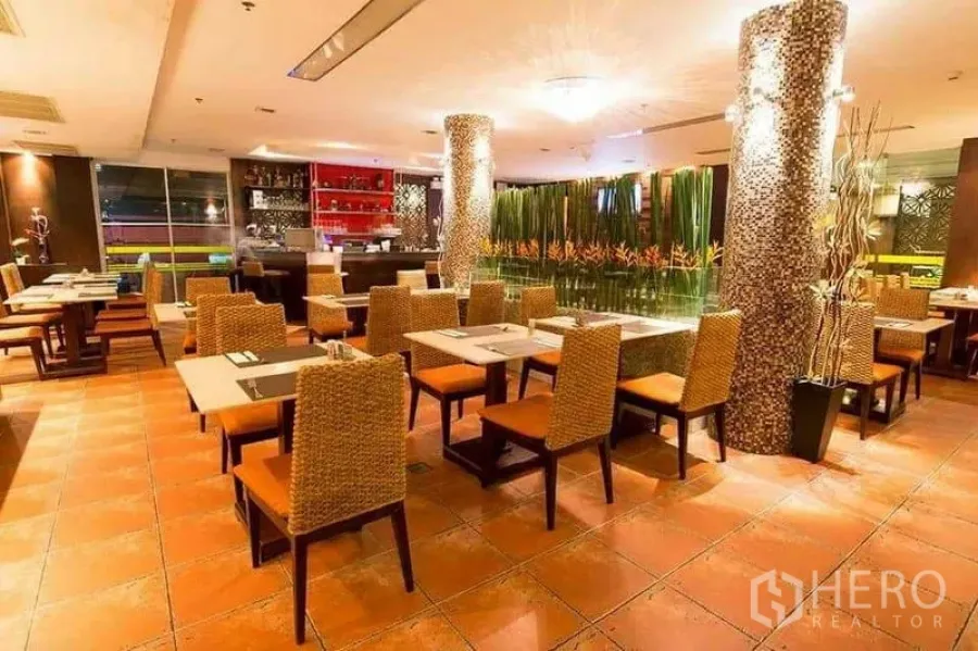 Retail Space for rent in Khlong Toei, Bangkok - Restaurant interior facing a bar with decorative plant divider and orange seats.