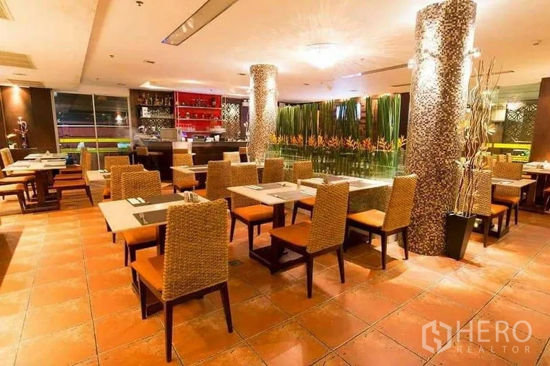 Retail Space for rent in Khlong Toei, Bangkok - Restaurant interior facing a bar with decorative plant divider and orange seats.