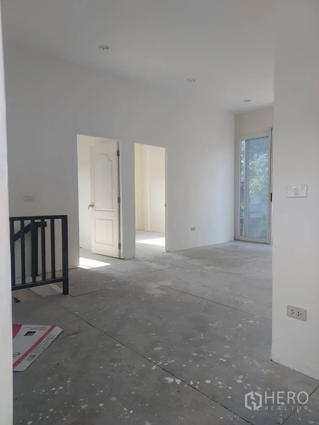Detached House for rent in Watthana, Bangkok - Bright upper floor landing with white walls, concrete floor and a sliding glass door facing greenery.