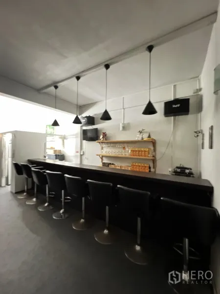 Shophouse for rent in Khlong Toei, Bangkok - Bright bar area with a row of stools, cone pendant lights and a glassware shelf.
