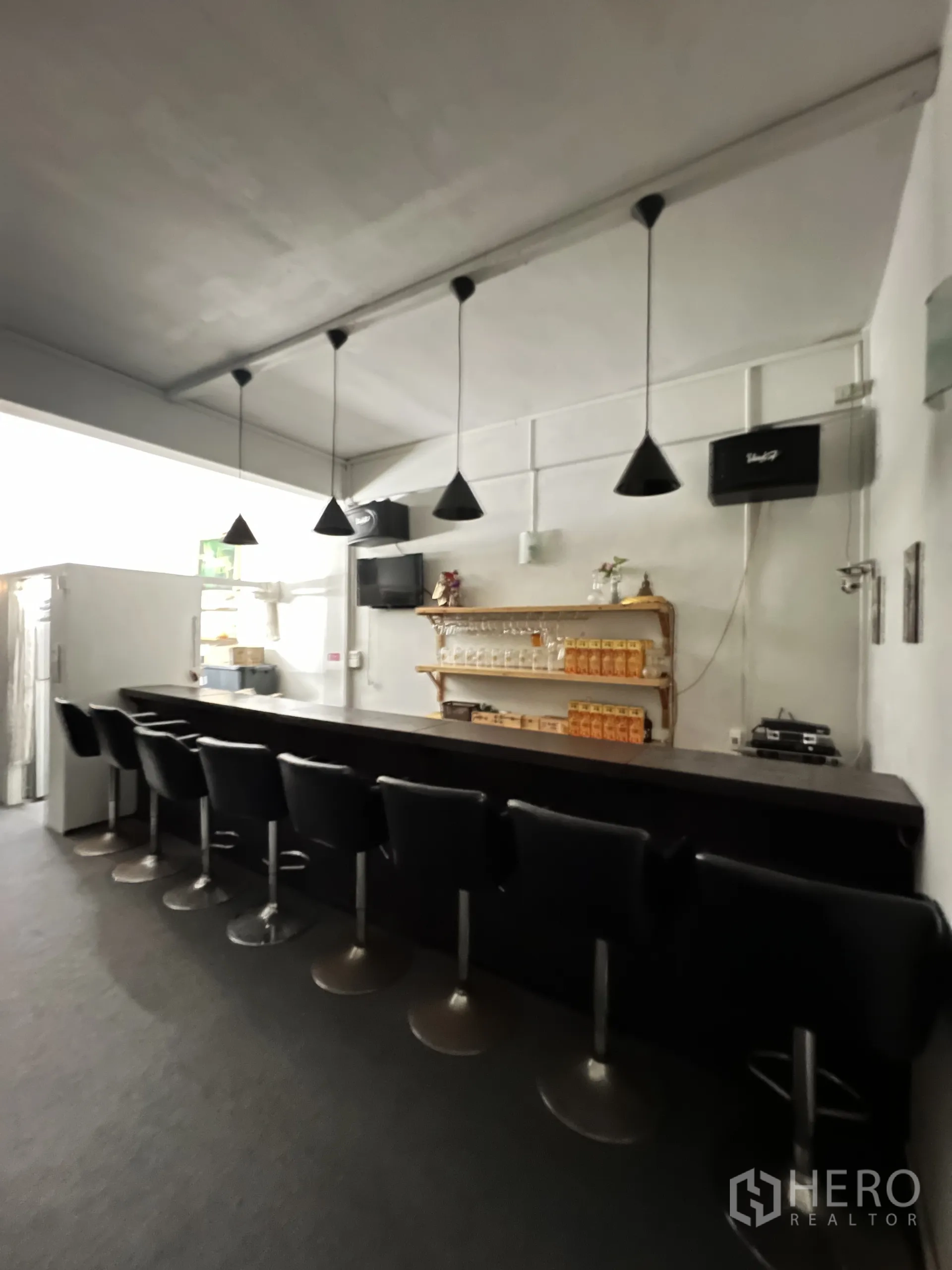 Shophouse for rent in Khlong Toei, Bangkok - Bright bar area with a row of stools, cone pendant lights and a glassware shelf.