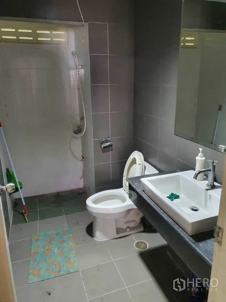 Townhouse for sale in Khlong Toei, Bangkok - Bathroom with walk-in shower, toilet, vanity, and gray tiles.